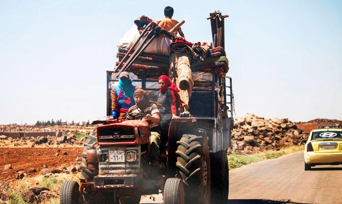 A Syrian family rides with belongings on a tractor-drawn trailer as they flee from fighting in the southern Syrian province of Daraa on June 21, 2018. (AFP)
