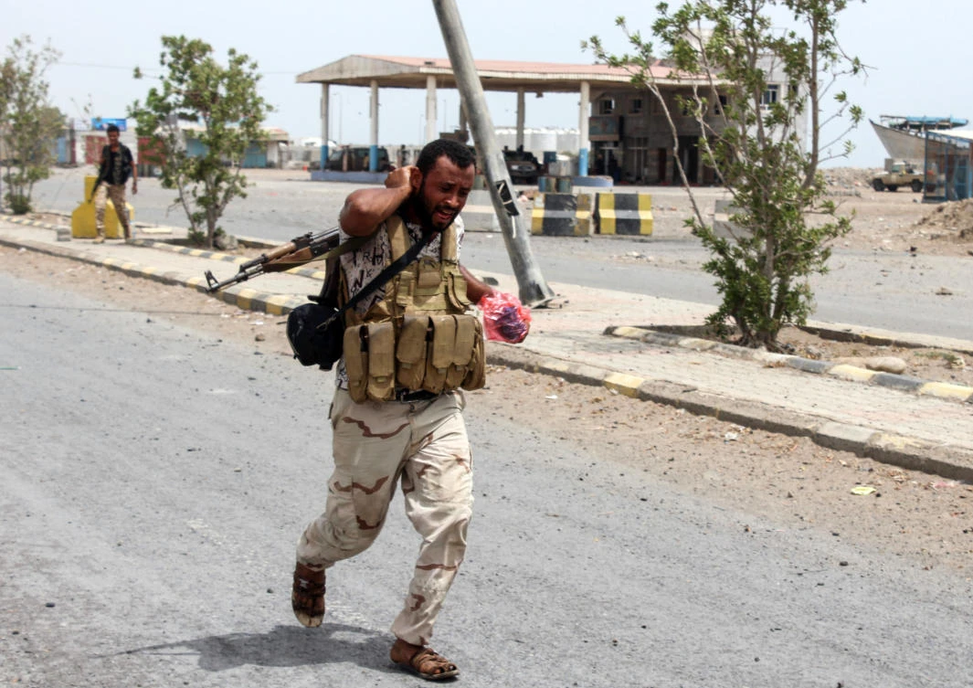 A Yemeni fighter from the Amalqa (“Giants“) Brigades, loyal to the Saudi-backed government, walks carrying a package along a road during the offensive to seize the Red Sea port city of Hodeida from Iran-backed Houthi milita (Saleh Al-Obeidi/AFP)
