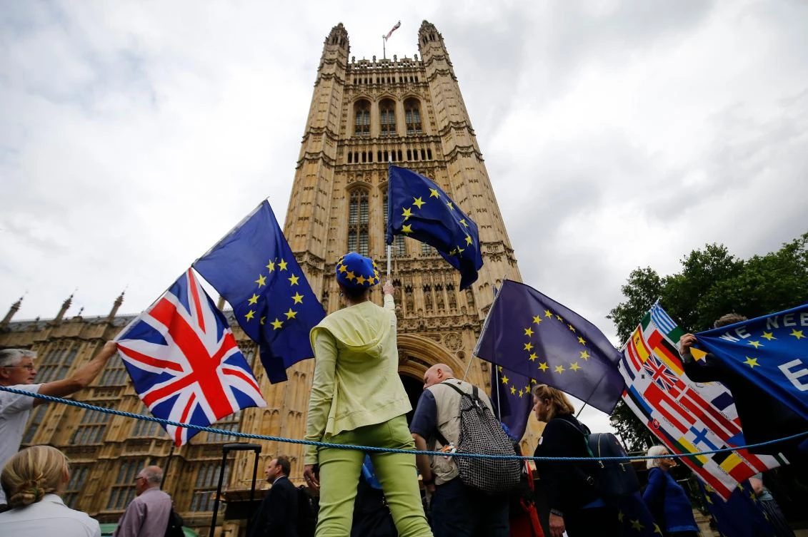 Pro-EU demonstrators hold placards and wave European Union flags during an anti-Brexit protest outside the Houses of Parliament in London on June 12, 2018. (AFP File Photo/ Tolga AKMEN)