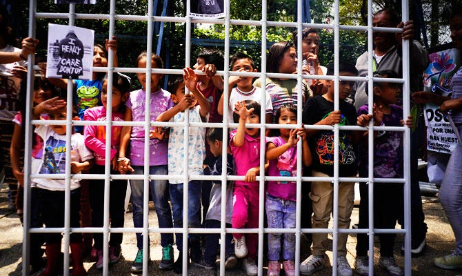 Children hold up a metal fence to symbolize immigrant children detained by US immigration authorities and separated from their families, as they pose for photographers outside the US embassy in Mexico City, on Tuesday, June 26, 2018. (AP)