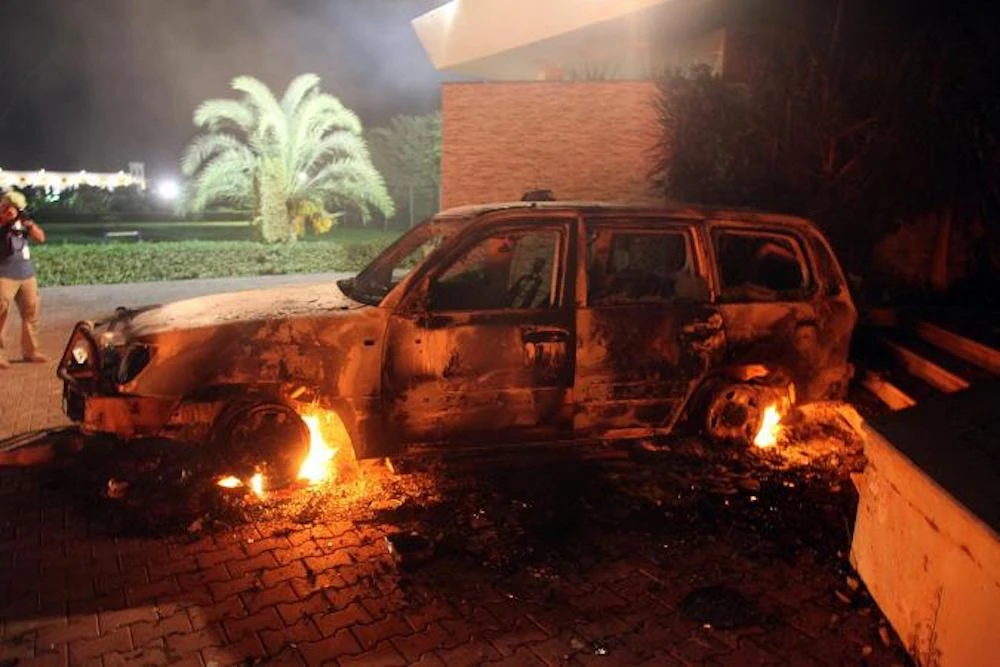 A vehicle sits smoldering in flames after being set on fire during the attack US consulate compound in Benghazi in 2012. (AFP)