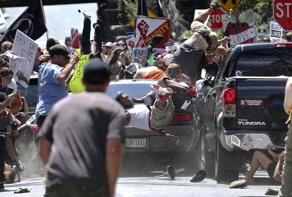 In this Aug. 12, 2017, file photo, people fly into the air as a vehicle is driven into a group of protesters demonstrating against a white nationalist rally in Charlottesville, Virginia, US. Federal hate crime charges have been filed against James Alex Fields Jr., accused of driving the car. (Ryan M. Kelly/The Daily Progress via AP, File)