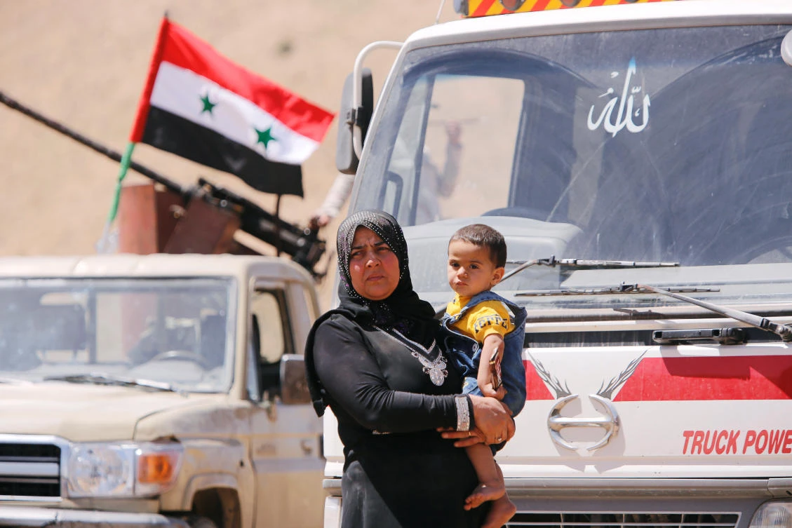 A Syrian refugee who left Lebanon holds a baby as she arrives in Qalamoun, Syria June 28, 2018. (Reuters)