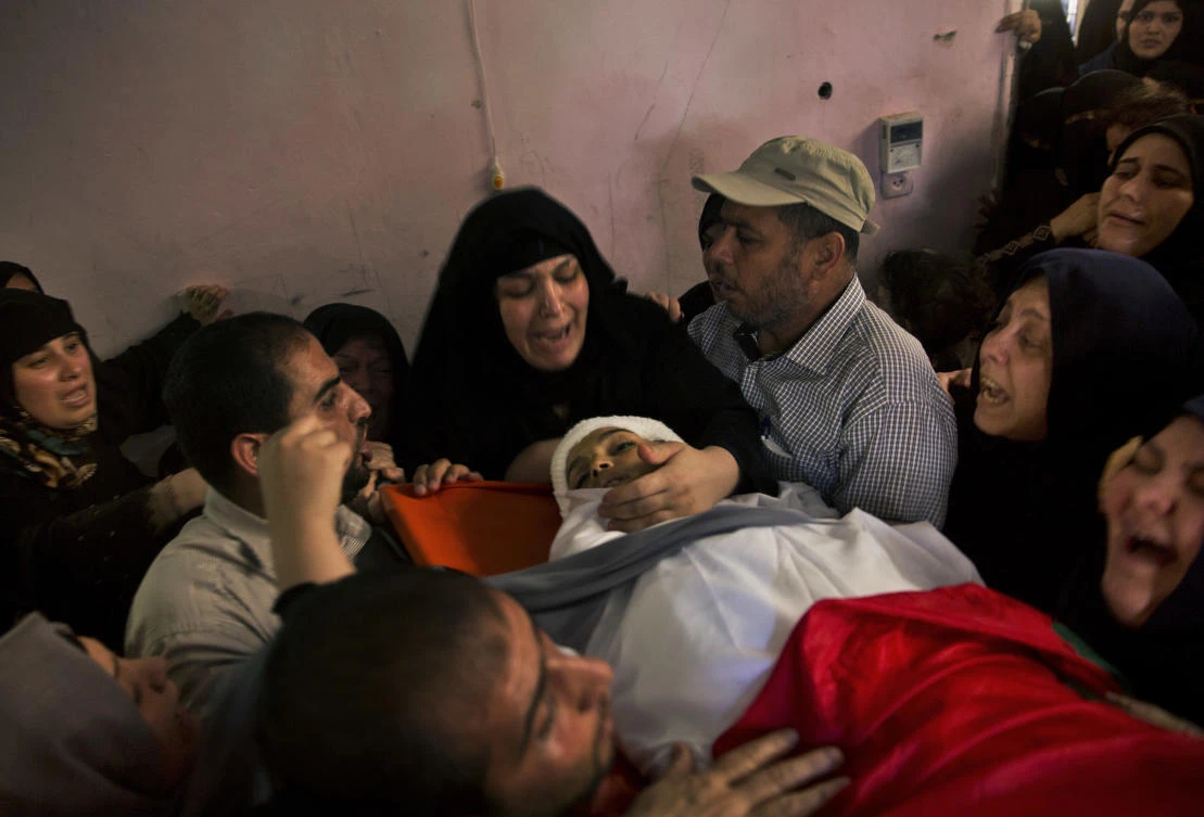 Relatives of 13 year-old Palestinian boy, Yasser Abu Al-Naja, mourn over his body during his funeral in the family house in town of Khan Younis, southern Gaza Strip, Saturday, June 30, 2018. (AP)