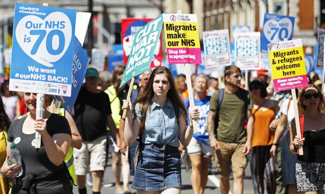 People holding placards attend a demonstration and celebration march to mark the 70th anniversary of the National Health Service (NHS), in central London on Saturday, June 30, 2018. (AFP)