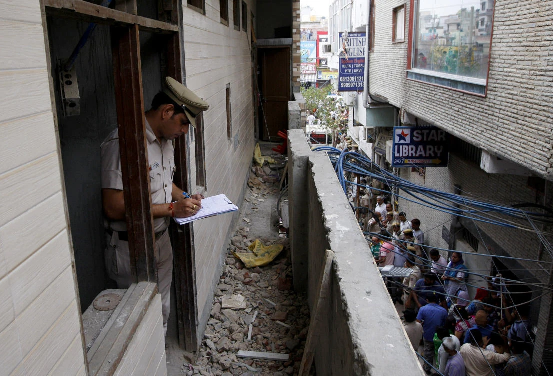 A policeman writes notes in the house where the bodies of eleven members of a family were found dead in Burari, in New Delhi, India, July 1, 2018. (Reuters)