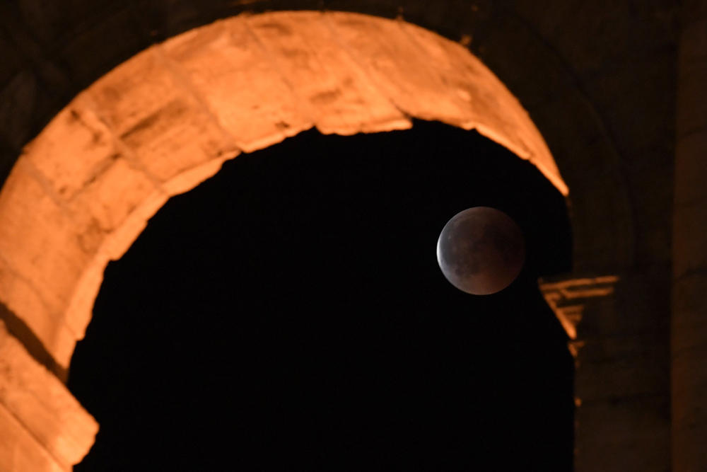 This picture shows the full moon during a 'blood moon' eclipse behind the ancient Colosseum on July 28, 2018. T(AFP / Tiziana Fabi)