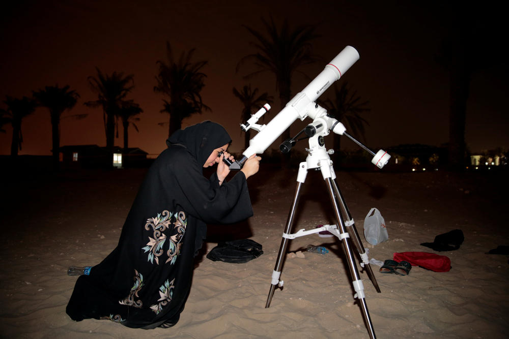 Sarah Al Muhairi, an aspiring Emirati astronomer, uses a telescope to view the lunar eclipse of a full "Blood Moon" at Al Sadeem Observatory in Al Wathba near Abu Dhabi, United Arab Emirates, on July 27, 2018. (REUTERS/Christopher Pike)