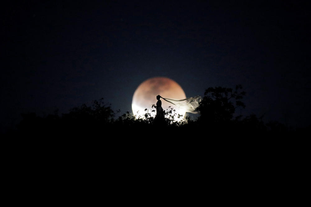 A bride poses for photo during a total lunar eclipse from in Brasilia, Brazil, July 27, 2018. (REUTERS/Ueslei Marcelino)