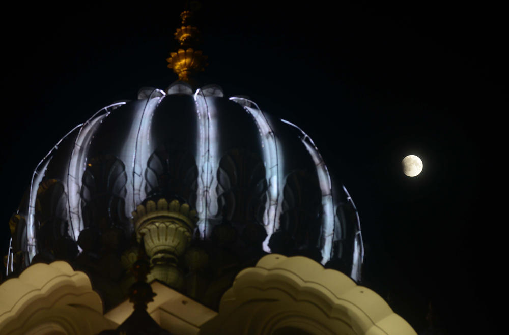 This picture shows the full moon during a 'blood moon' eclipse beside the Golden temple in Amritsar early on July 28, 2018. (AFP / NARINDER NANU)