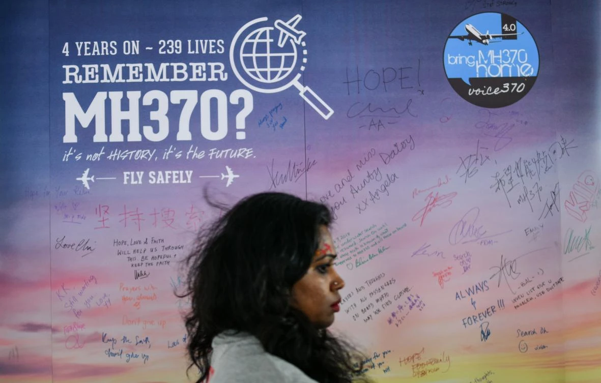 A woman walks past a banner bearing solidarity messages for passengers of the missing Malaysia Airlines flight MH370, during a memorial event in Kuala Lumpur on March 3, 2018 ahead of the fourth anniversary of at the ill-fated plane’s disappearance. (AFP)