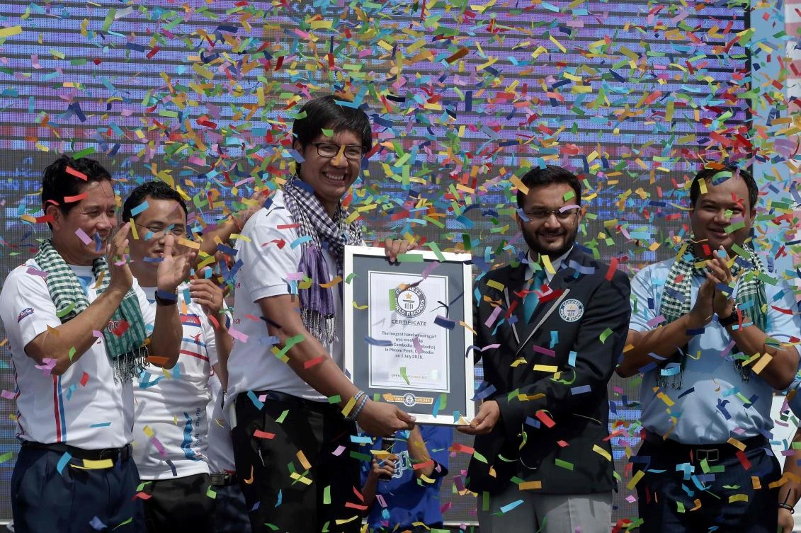 Swapnil Dangarikar, second right, an adjudicator from the Guinness World Records, awards a certificate to Sann Vathana, third left, from the GoGo Cambodia movement, after a 1,149.8 meter-long krama scarf was named as the world’s longest hand-woven scarf. (AFP)