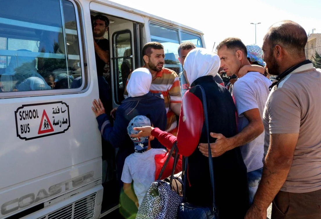 Syrian refugees board a minibus evacuating them from Lebanon at the Masnaa crossing on the Lebanon-Syria border on July 1, 2018, on their way back to Damascus. (AFP)