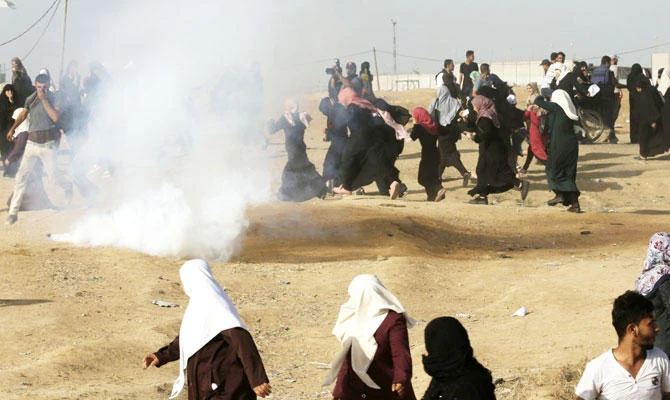 Protesters flee from incoming tear gas canisters fired by Israeli forces during a demonstration by Palestinian women along the border east of Gaza City on Tuesday. AFP