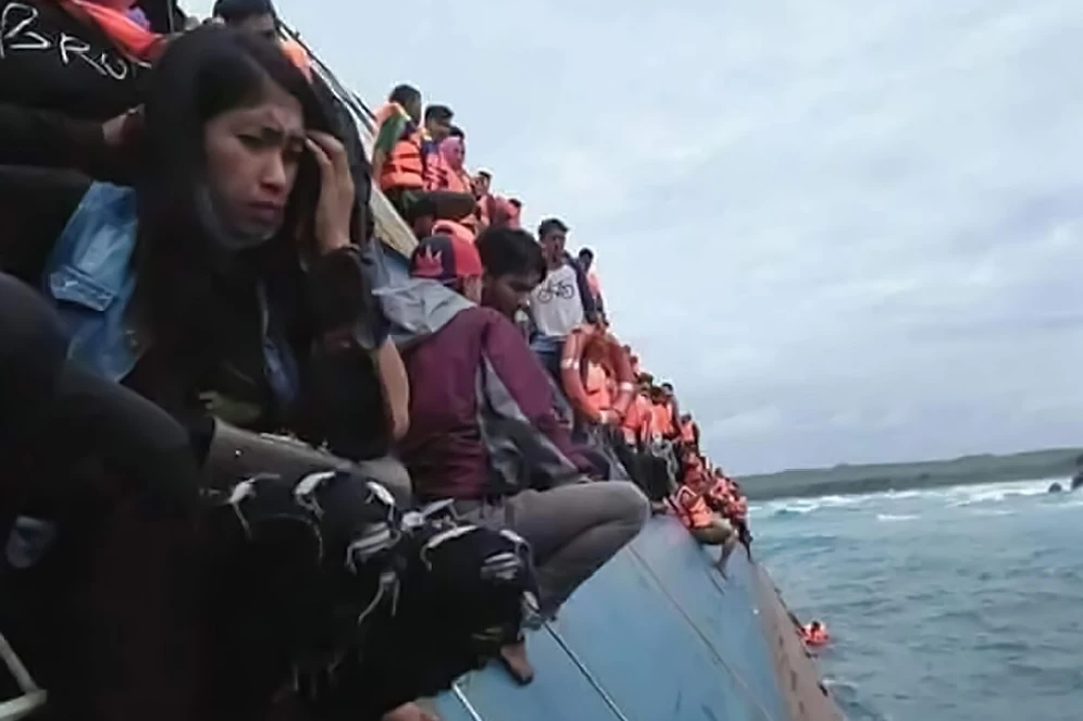 A handout picture Indonesia’s Badan Nasional Penanggulangan Bencana shows passengers clinging to the side of a ferry as it sank off the coast of Selayar island, in South Sulawesi province on Tuesday afternoon, July 3. (Badan Nasional Penanggulangan Bencana via AFP)