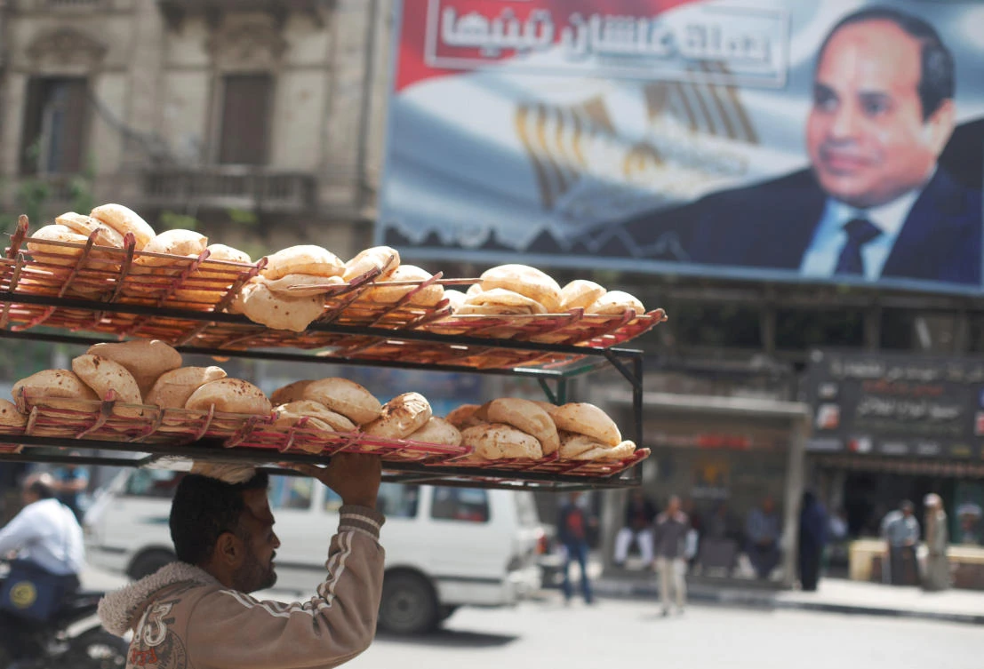 A man carries breads along a busy street past a banner for Egyptian President Abdel Fattah El-Sisi in Cairo. (Reuters)