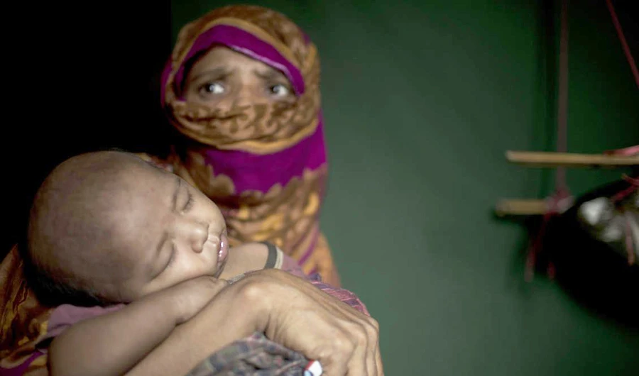 In this Monday, June 25, 2018, photo, "S" holds her baby boy as she sits in her shelter in Kutupalong refugee camp in Bangladesh. (AP)