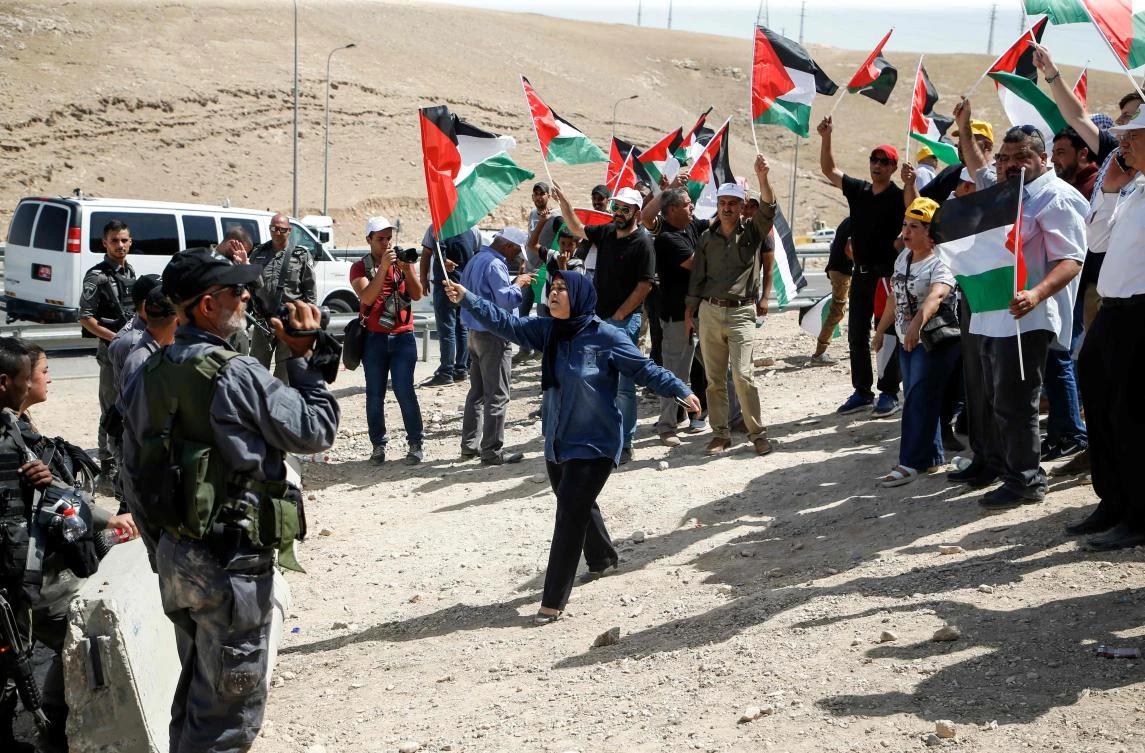 Demonstrators wave Palestinian flags as they protest against Israeli demolitions in the Palestinian Bedouin village of Khan al-Ahmar, east of Jerusalem in the occupied West Bank on July 4, 2018. (AFP)