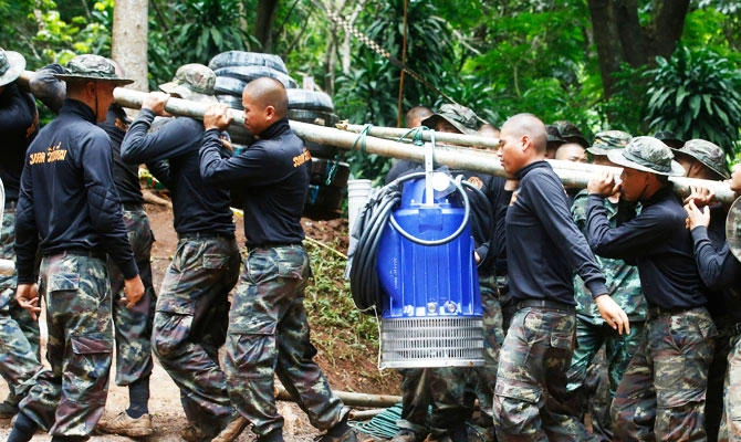 Soldiers carry a pump to help drain the rising flood water in a cave where 12 boys and their soccer coach have been trapped since June 23, in Mae Sai, Chiang Rai province, in northern Thailand on Friday, July 6, 2018. (AP)