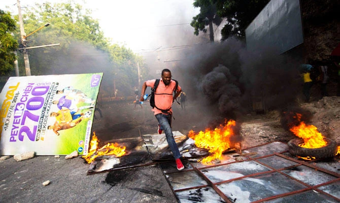 A man runs past a burning barricade during a protest over the cost of fuel in Port-au-Prince, Haiti, on Friday, July 6, 2018. (AP)