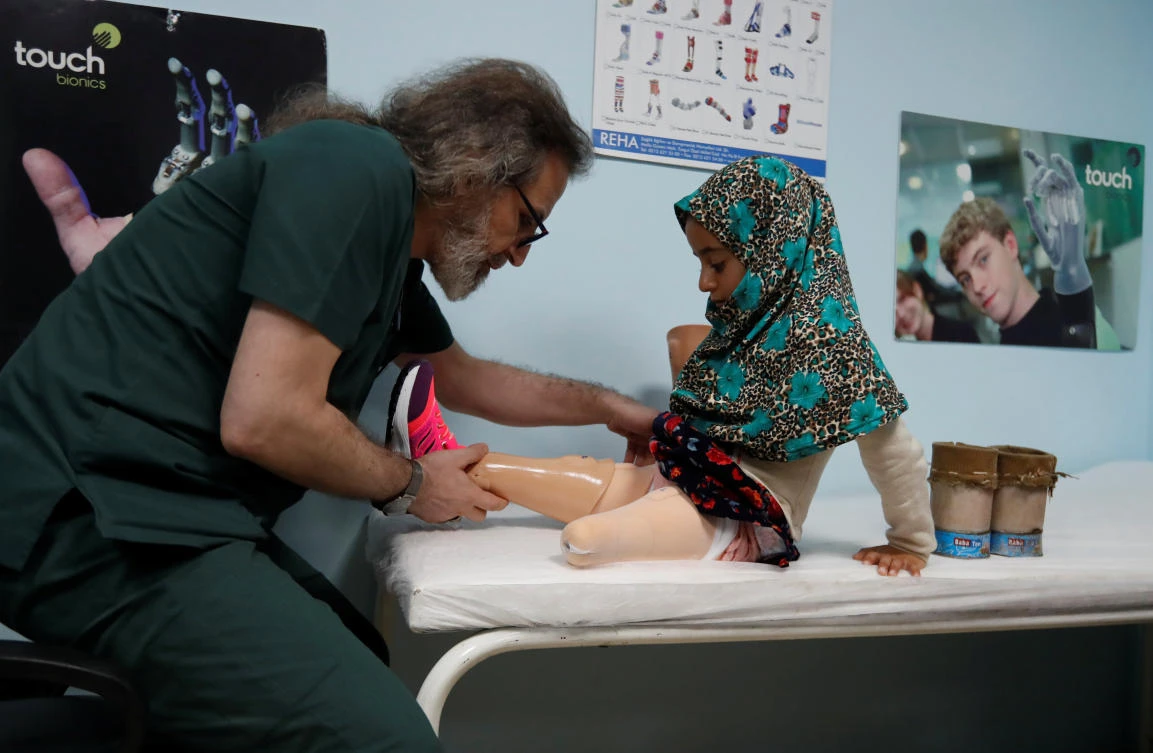 Technician Mehmet Zeki Culcu fit the artificial legs of Maya Meri at a prosthetic center in Istanbul. (Reuters)
