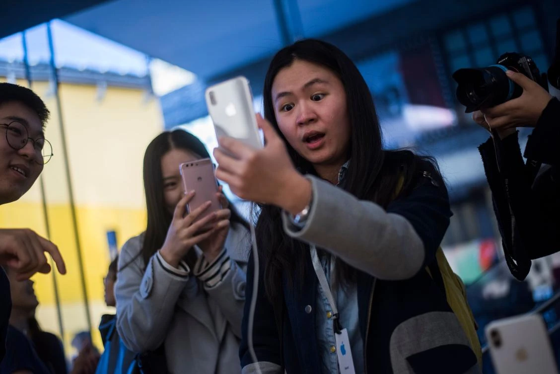 A Chinese woman reacts while setting up the facial recognition feature on her iPhone X inside an Apple showroom in Beijing. (AFP)