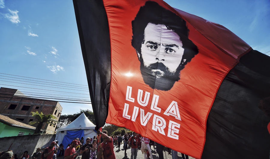A supporter of ex-President Luiz Inacio Lula da Silva holds a flag that reads in Portuguese: "Free Lula," in front of the Federal Police Department where Da Silvia is serving jail time in Curitiba, Brazil, on, July 8, 2018. (AP Photo/Denis Ferreira Netto)