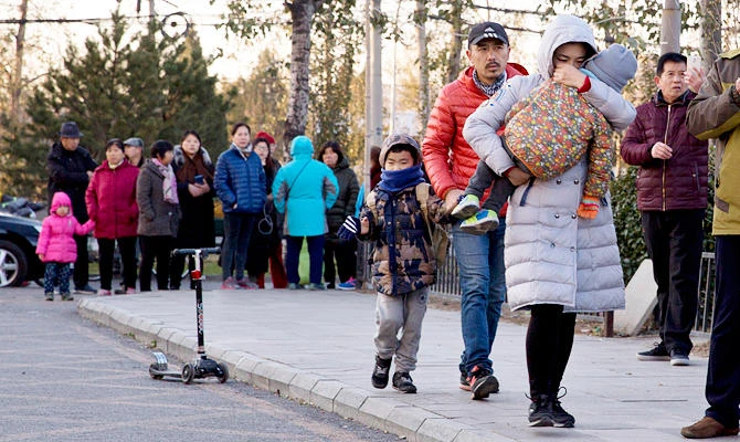 A woman carries a child as they arrive at the RYB kindergarten in Beijing, China, in this Nov. 24, 2017 file photo. (AP)