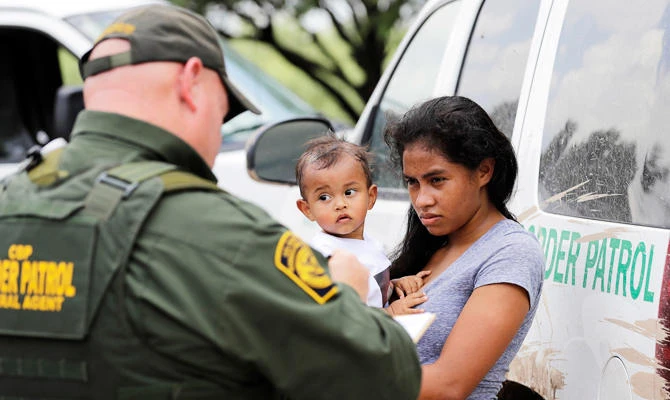 In this June 25, 2018 file photo, a mother migrating from Honduras holds her 1-year-old child as surrendering to U.S. Border Patrol agents after illegally crossing the border, near McAllen, Texas. (AP)