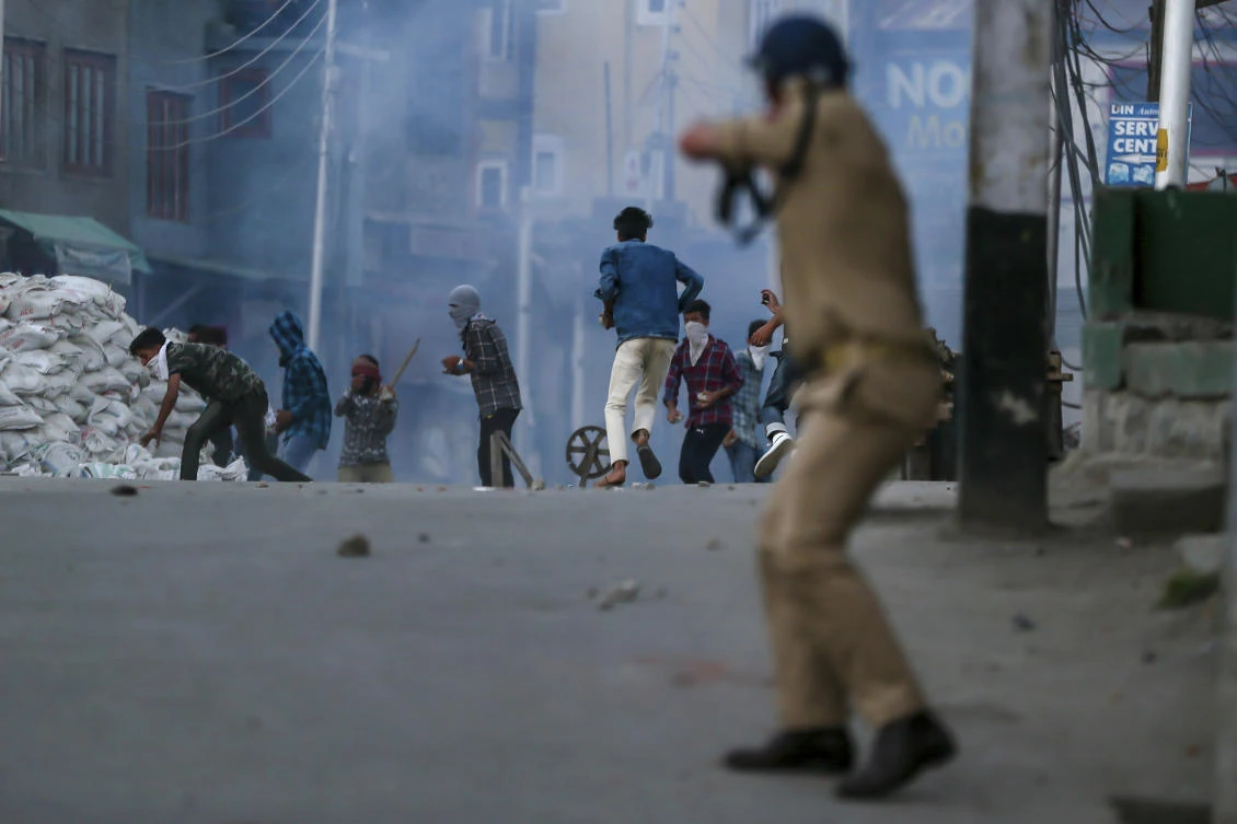 Protesters run for cover as a policeman fires pellet gun at them during a protest against the killing of civilians in in Srinagar of Indian controlled Kashmir. (AP)