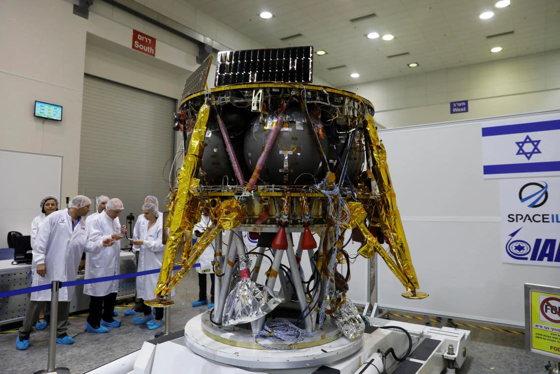 Israeli scientists stand next to an unmanned spacecraft which an Israeli team plans to launch into space at the end of the year and to land it on the Moon next year, in Yahud, Israel, July 10, 2018. (Reuters)