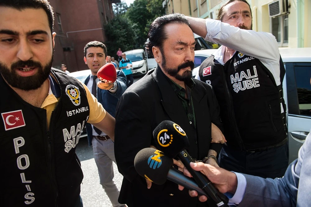 Turkish police officers escort televangelist and leader of a sect Adnan Oktar, center, on Wednesday, July 11 after his arrest on fraud charges. (Dogan News Agency / AFP)