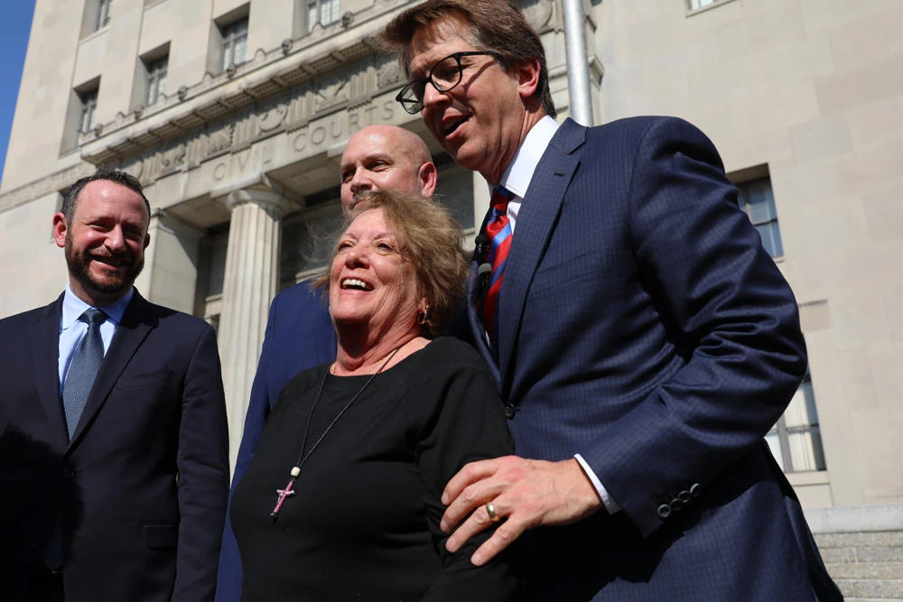 Plaintiff Gail Ingham, foreground, of O'Fallon, Missouri., stands outside the civil courthouse with attorneys Lee Cirsch, from left, Eric Holland and Mark Lanier following a verdict against health care giant Johnson & Johnson on July 12, 2018, in St. Louis. (Christian Gooden/St. Louis Post-Dispatch via AP)