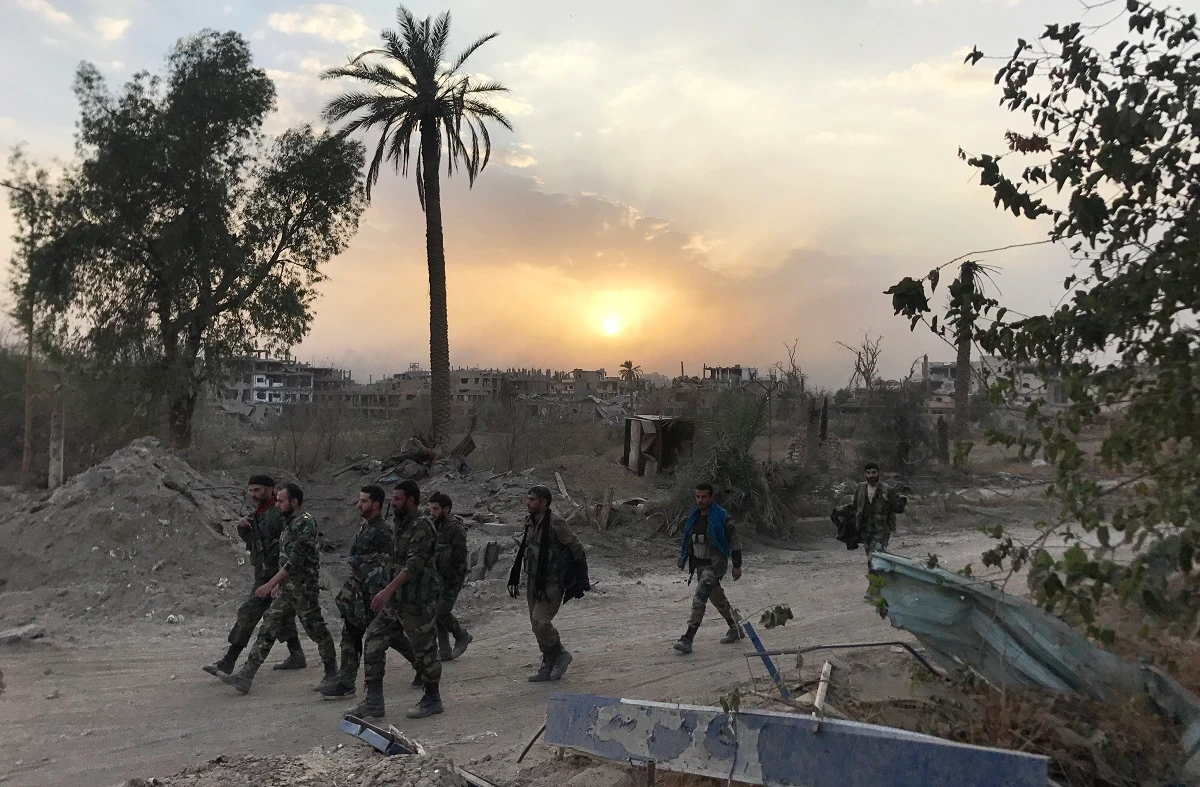 Syrian government forces walk through a road in a northeastern district of Deir Ezzor after retaking the city from Deash militants in this on November 5, 2017 photo. (AFP)