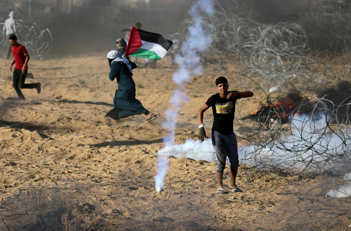 Palestinians react to tear gas fired by Israeli troops during a protest at the Israel-Gaza border, during which a Palestinian teenager was shot dead by Israeli soldiers. (Reuters)