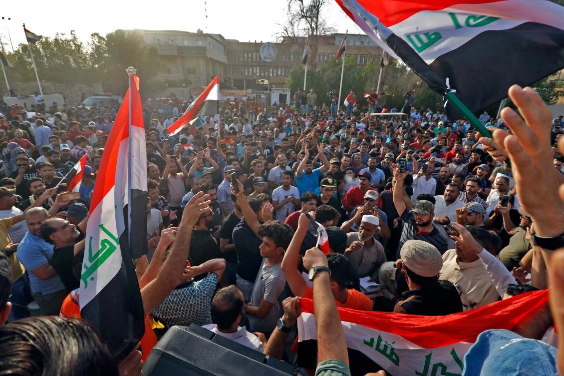 Iraqi protesters shout slogans and wave national flags, during a demonstration in the southern city of Basra, as they protest against poor services, unemployment and corruption. (AFP)