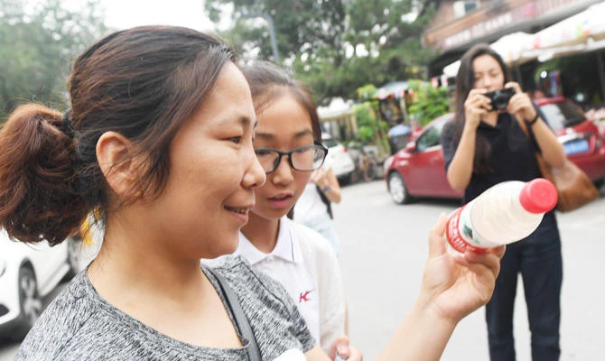 This photo taken on July 12, 2018 shows a woman looking at polluted water in a mineral water bottle at a roving exhibition created by Chinese performance artist Nut Brother, known for his advocacy work on environmental and social issues, in Beijing. (AFP)