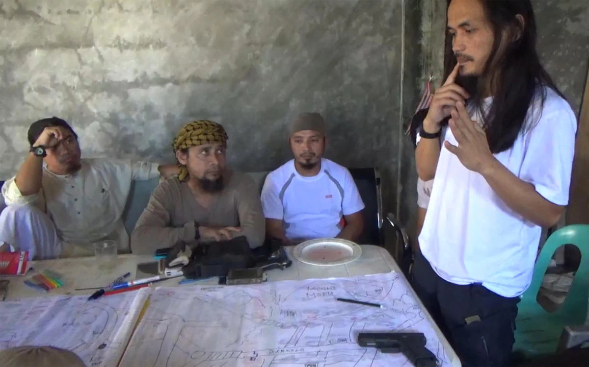A screengrab from a video released by the Philippine Army on June 18, 2017 shows Abdullah Maute, right, looking at an improvised map of Marawi, while Isnilon Hapilon, second left, leader of hardline group Abu Sayyaf looks on, as they plan an attack on Marawi at an undisclosed location on Mindanao island. (Philippine Army via AFP)