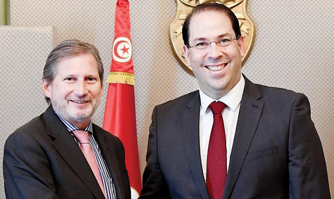 Tunisian Prime Minister Youssef Chahed shakes hands with the European Commissioner for European Neighborhood Policy and Enlargement Johannes Hahn, left, on Thursday in Tunis. AFP