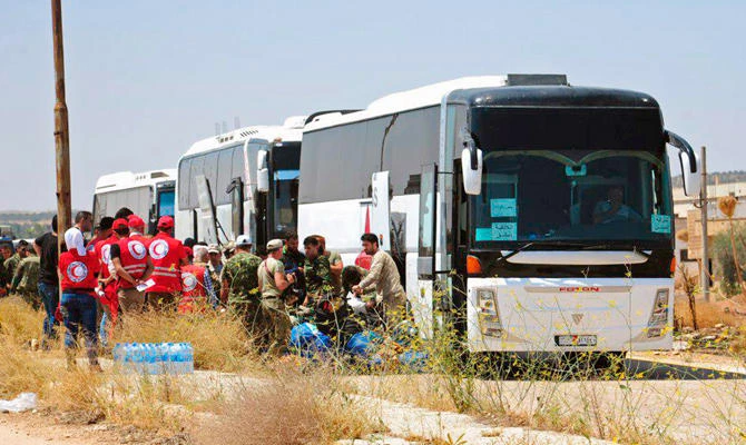 Syrian government forces and Syrian Arab Red Crescent oversee the evacuation by buses of opposition fighters and their families from the southern province of Daraa, Syria, in this July 15, 2018 photo. (AP)