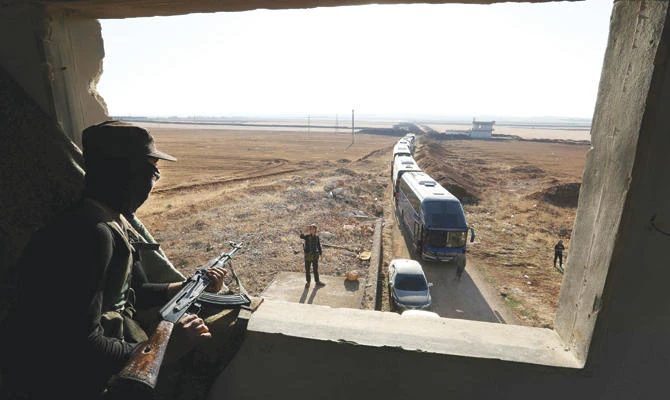 A member of Hayat Tahrir Al-Sham group watches as a convoy of busses gets ready to enter the towns of Fuaa and Kefraya to evacuate their residents on Wednesday. (AFP)