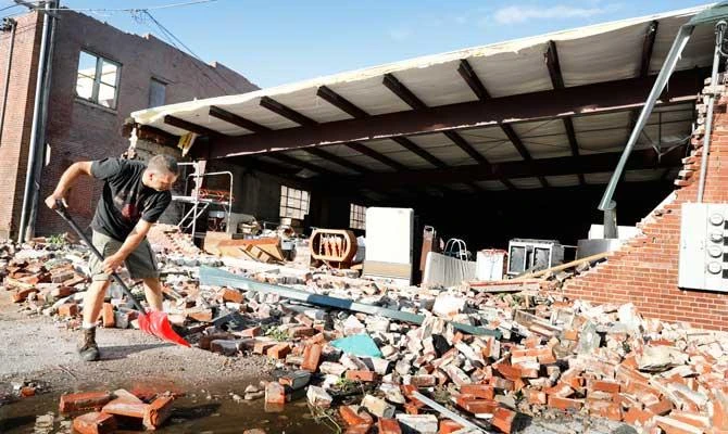 Roy Schweinebart, of Marshalltown, Iowa, shovels bricks from a tornado-damaged building near Main Street, Thursday, July 19, 2018, in Marshalltown, Iowa. (AP)