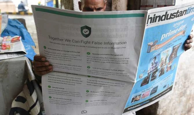 This photo illustration shows an Indian newspaper vendor reading a newspaper with a full back page advertisement from WhatsApp intended to counter fake information, in New Delhi on July 10, 2018. (AFP)