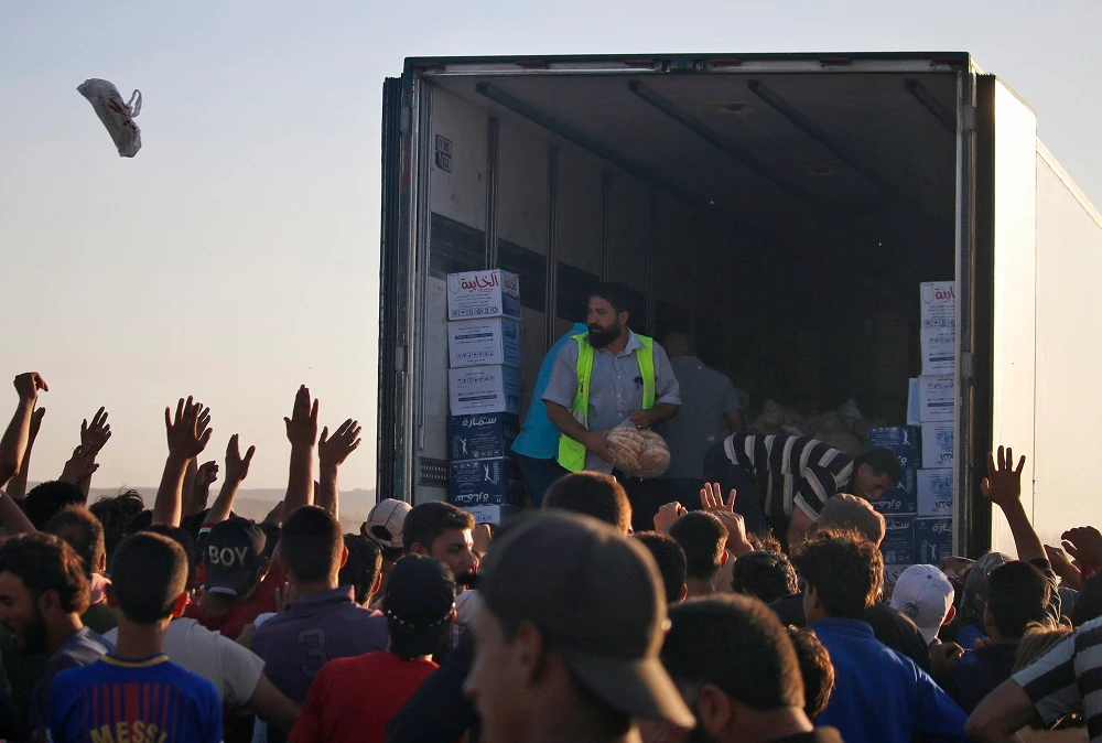 Displaced Syrians from the Daraa province fleeing shelling by pro-government forces gather to receive aid food in a makeshift camp near the Jordanian border and the town of Nassib, southern Syria, on July 2, 2018. (File photo: AFP)