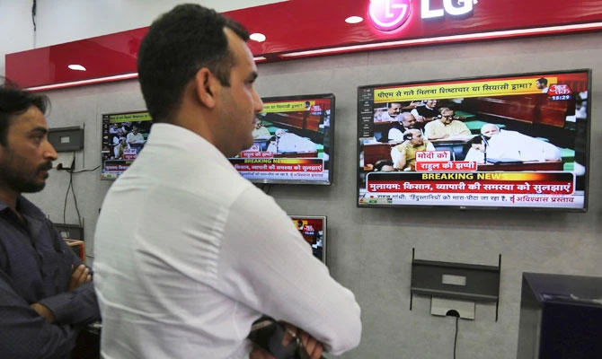 Indians watch television showing Congress party President Rahul Gandhi hug Prime Minister Narendra Modi during parliament session, at an electronics shop in Jammu, India, Friday, July 20, 2018. (AP)