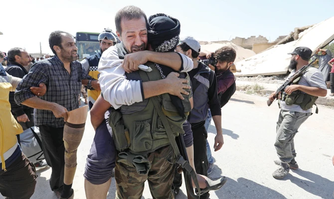 A prisoner released by the regime embraces an opposition fighter upon his arrival at Al-Eis crossing point, south of Aleppo, on Friday. (AFP)