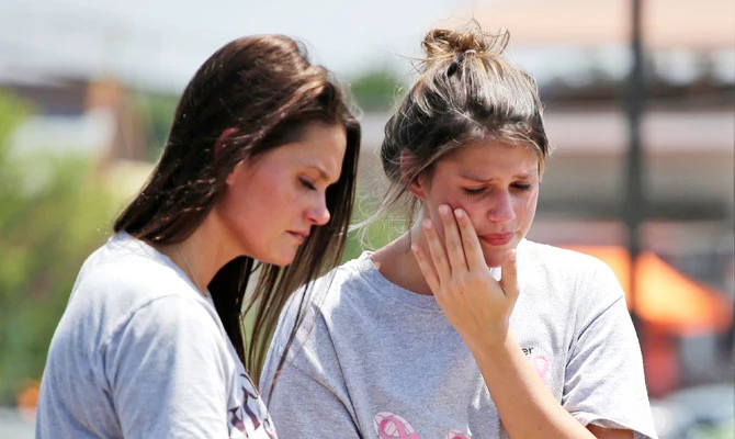Rina Bernard, left, and Keri Johnson leave flowers on a car believed to belong to a victim of a duck boat accident on Table Rock Lak, Friday, July 20, 2018 in Branson, Mo. (AP)