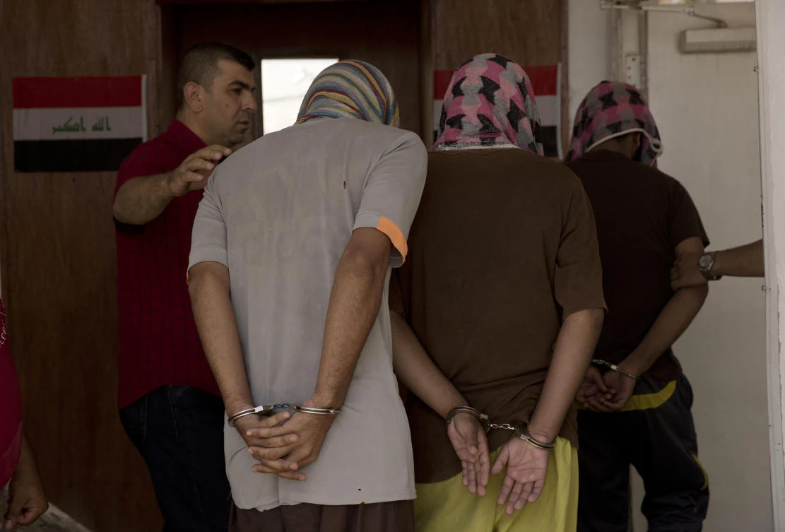 A guard leads three death row prisoners Ismail Saleh, left, Ahmed Nijm, center, and Quteiba Younis, right, to the Eagles’ Cell counterterrorism intelligence office in Baghdad. (File Photo: Maya Alleruzzo/AP)