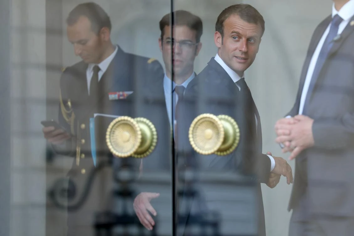 In this file photo taken on May 28, 2018 French President Emmanuel Macron stands with advisers behind the main entrance glass doors of the Elysee presidential palace in Paris. (AFP)