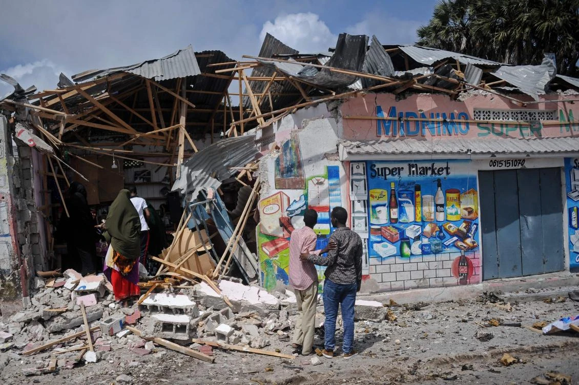 People look at damaged shops after two car bombs were detonated and three Shabab gunmen were shot dead after exchanging fire with security forces outside the presidential palace in Mogadishu, on July 14, 2018. (File Photo: AFP/Mohamed Abdiwahab)